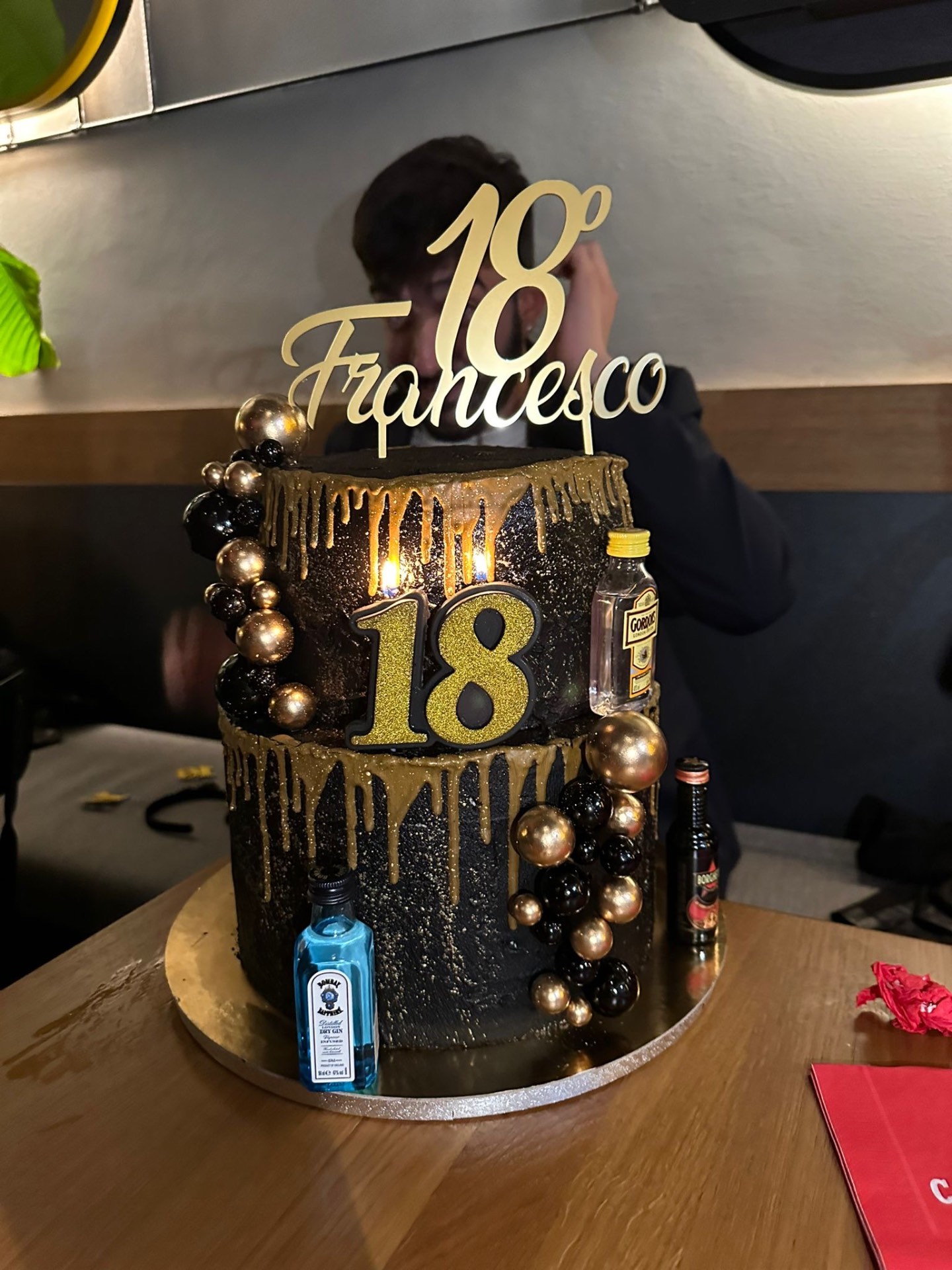 Torta nera a due piani con drip oro e scritta 18 Francesco