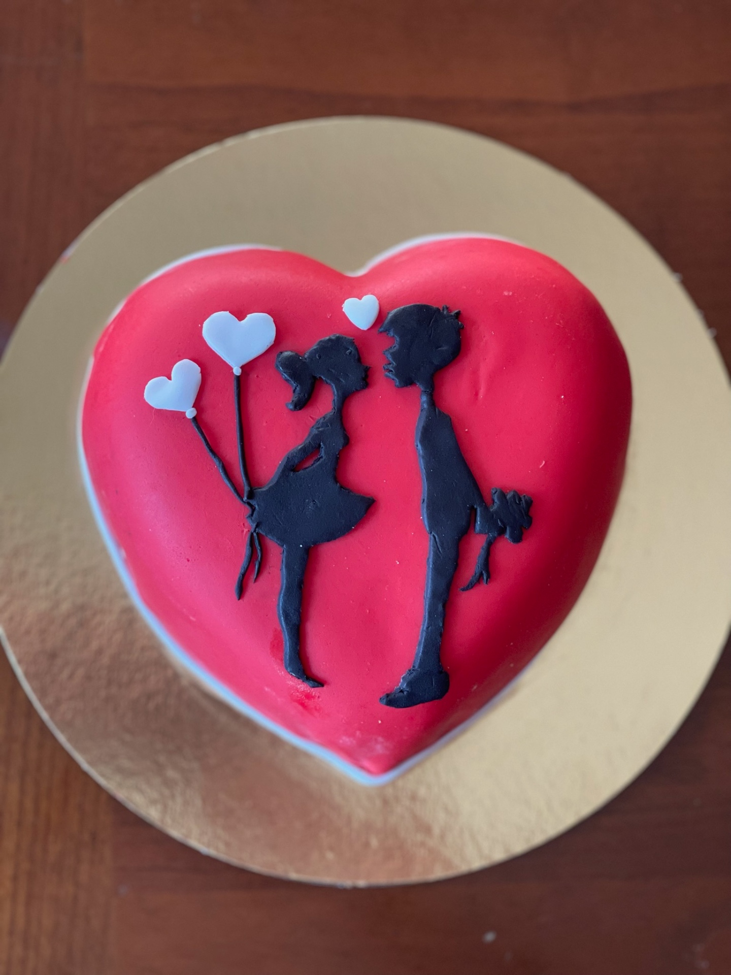 Torta a cuore rossa con silhouette di innamorati e palloncini