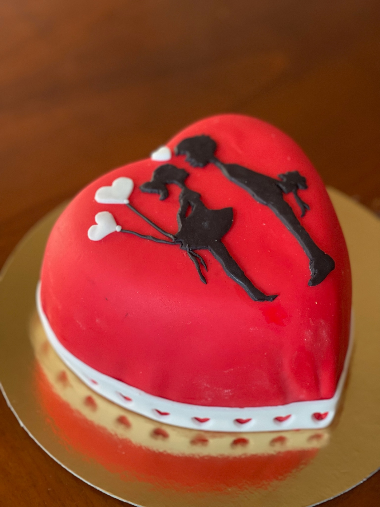 Torta a cuore rossa in pasta di zucchero con decorazioni bianche